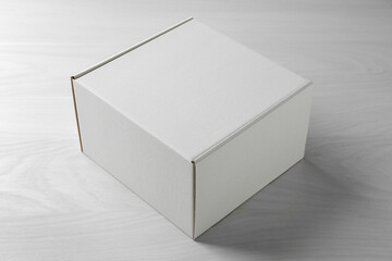 Wall Mural - One blank cardboard box on white wooden background. Mockup for design