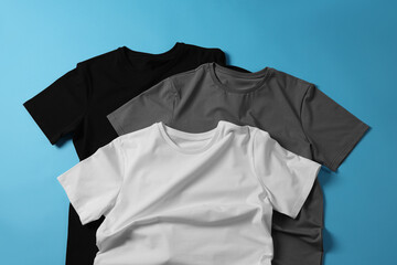 Wall Mural - Blank t-shirts on light blue background, flat lay. Mockup for design