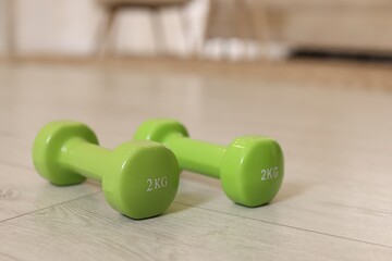 Wall Mural - Green dumbbells on floor indoors, closeup. Fitness equipment