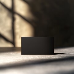 Poster - Minimalist Black Business Card Mockup with Shadow Play on Concrete Surface for Branding Presentation