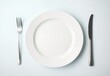 © ma - White plate with knife and fork on a white background, top view.