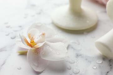 Wall Mural - Orchid flower and spa stones on white marble table, closeup