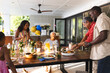 © WavebreakMediaMicro - Sharing laughter and conversation, multiracial family having meal together in garden around table