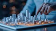 © saichon - A person points at a scaled architectural model of a city, showcasing detailed buildings and illuminated areas, emphasizing urban planning and design.