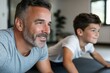 © Milos - A smiling father and son lying on mats in a gym, fostering a sense of joy and teamwork while participating in a fun fitness activity.