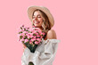 © HBS - Portrait of a beautiful tender young woman smiling with closed eyes and holding spring pink flowers on a soft pink background. Celebrating International Women's Day.