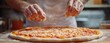 © mrbee - A chef sprinkling cheese over a freshly prepared pizza dough on a wooden table, showcasing culinary skill.