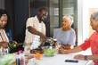 © WavebreakMediaMicro - diverse family preparing meal together in modern kitchen, smiling warmly, at home