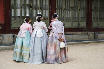 Back view Korean women in colorful traditional Hanbok costumes walking in Gyeongbokgung Palace most popular tourist attraction in Seoul, South Korea