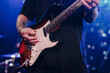 © tsuguliev - Concert view of an electric guitar player with vocalist and rock band performing in a club, male musician guitarist on stage with audience in a crowded concert show club hall arena, hands on a guitar