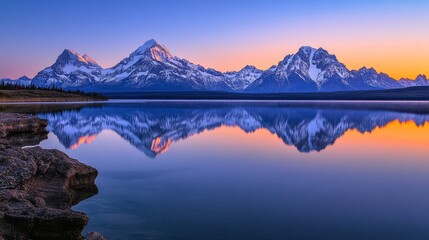A tranquil sunrise over a calm lake, with snow-capped mountains mirrored perfectly on the still water, creating a peaceful, serene atmosphere.