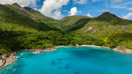 Wall Mural - A calm bay with turquoise water, surrounded by lush green hills and a small sandy beach. Seychelles, Mahe.