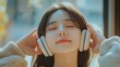 © Ludmila Zabaranilova - Asian young woman listening to music on headphones relaxing on
