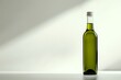 © Undersea - Green glass bottle with olive oil on white surface against light gray background with diagonal shadow, minimalist composition for food and beverage marketing.