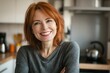 © Enigma - Confident and happy redhead mature woman smiling, enjoying her time in a modern kitchen, radiating positivity and warmth in a domestic setting