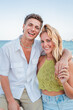 © Jose Calsina - Joyful Young Couple Embracing Each Other with Smiles Against the Ocean on a Beautiful Sunny Day, Two people enjoying their summer vacations on the beach. Portrait of friends at coastal sea shore