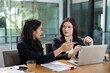 © Natee Meepian - Engaged female colleagues reviewing project plans and collaborating on analysis in a contemporary office.