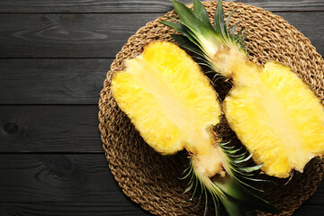 Wall Mural - Halves of ripe pineapple on black wooden table, top view. Space for text