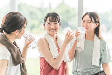 Poster - スポーツジムのヨガ教室で休憩をしながらプロテインや水を飲むする女性達
