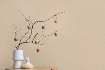 Wall Mural - Vase with tree branches, Easter eggs and decorative rabbit on table near beige wall