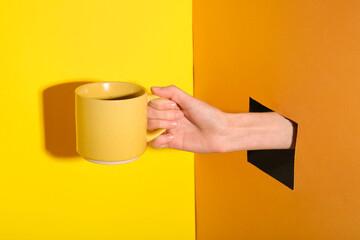 Wall Mural - Female hand with ceramic mug visible through hole in color paper