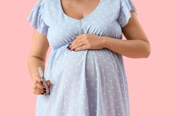 Wall Mural - Young pregnant woman with lancet pen on pink background, closeup. Gestational diabetes concept