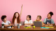 © Prostock-studio - Industrious red haired girl with friends studying at desk against pink background, blank space. Panorama