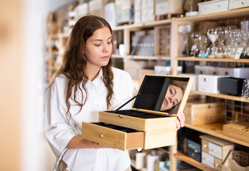 Wall Mural - Portrait of young woman searching wooden box for jewelry storage at store