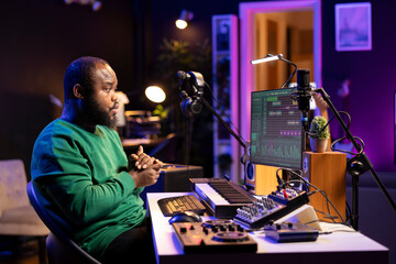 Poster - African american sound engineer using midi controller notes to add audio effects in post production, editing tracks with digital software and mixing console. Male musician in home studio.