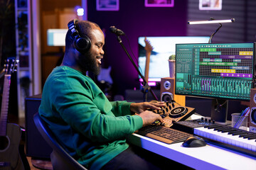Fototapete - Confident music engineer working on mixing console in home studio, producing new sounds for a song and editing volume levels in daw software. Audio technician recording acoustic files.