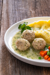 Wall Mural - Boiled meatballs in dill sauce with mashed potatoes and boiled carrot and green peas on wooden table	