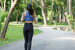 © crizzystudio - Young sporty woman jogging along a path in a lush green park, relishing her workout and embracing a healthy lifestyle amidst the serene beauty of nature on a sunny morning