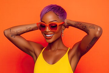 Wall Mural - an attractive, smiling woman with short, purple hair, wearing orange sunglasses and sportswear, posing in front of the camera on a yellow background and covering her ears