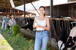 © JackF - Portrait of cheerful young girl standing with glass of fresh milk near stalls with cows on dairy farm on sunny summer day