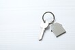 © Sunlight - Metallic key with keychain in shape of house on white background