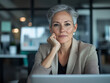 © CarloSanchezPereyra - Mature woman with short gray hair, thoughtfully working on a laptop in an office.