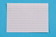 © nahhan - A top-down shot of a single white, ruled index card with a red line at the top, placed against a blue background