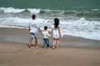 © alexkoral - back of family with a child boy son walking along the beach by the sea in summer