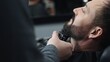 © rogerphoto - Skilled barber grooming client's beard using electric razor, delivering precise styling within contemporary barbershop setting