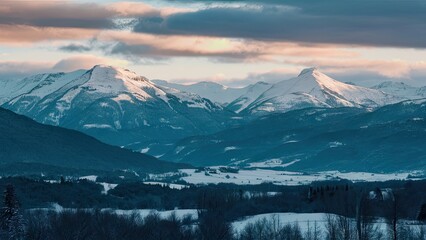 Wall Mural - Majestic panoramic view of snow-covered mountains in shades of blue and white, with a tranquil valley in the foreground under a cloudy sky.