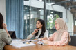 © wichayada - Women discussing project strategies in a contemporary office setting.
