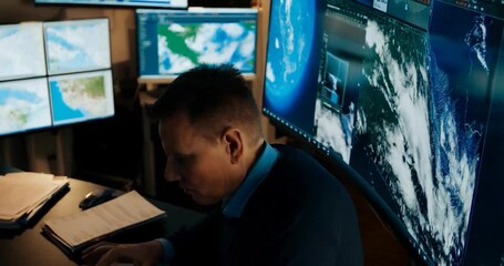 Poster - Man Working On Monitor Screen in A Dark Setting Focus On Detailed Examination of World Maps and Data