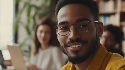 Wall Mural - Smiling man in glasses with colleagues in background.