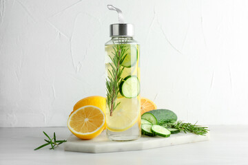 Wall Mural - Lemon water in bottle, rosemary, fresh fruits and cucumber on light table