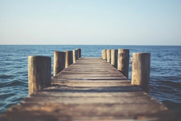 Poster - Wooden pier extending into calm waters under a clear blue sky during a serene morning. Generative AI