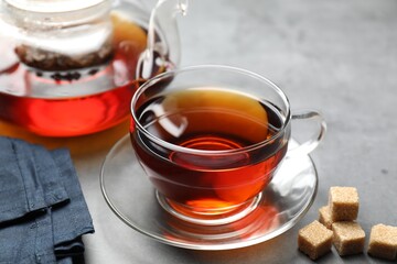 Wall Mural - Aromatic black tea and brown sugar cubes on light grey table, closeup