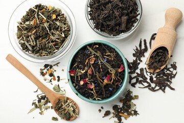 Wall Mural - Different dry tea leaves on white table, flat lay