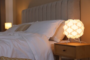 Wall Mural - Glowing lamp on nightstand near bed indoors