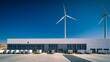 © alinka - Modern warehouse with wind turbines under a clear blue sky.