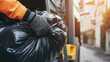 © Vasiliy - Hand in orange uniform collecting garbage bags. Waste management service